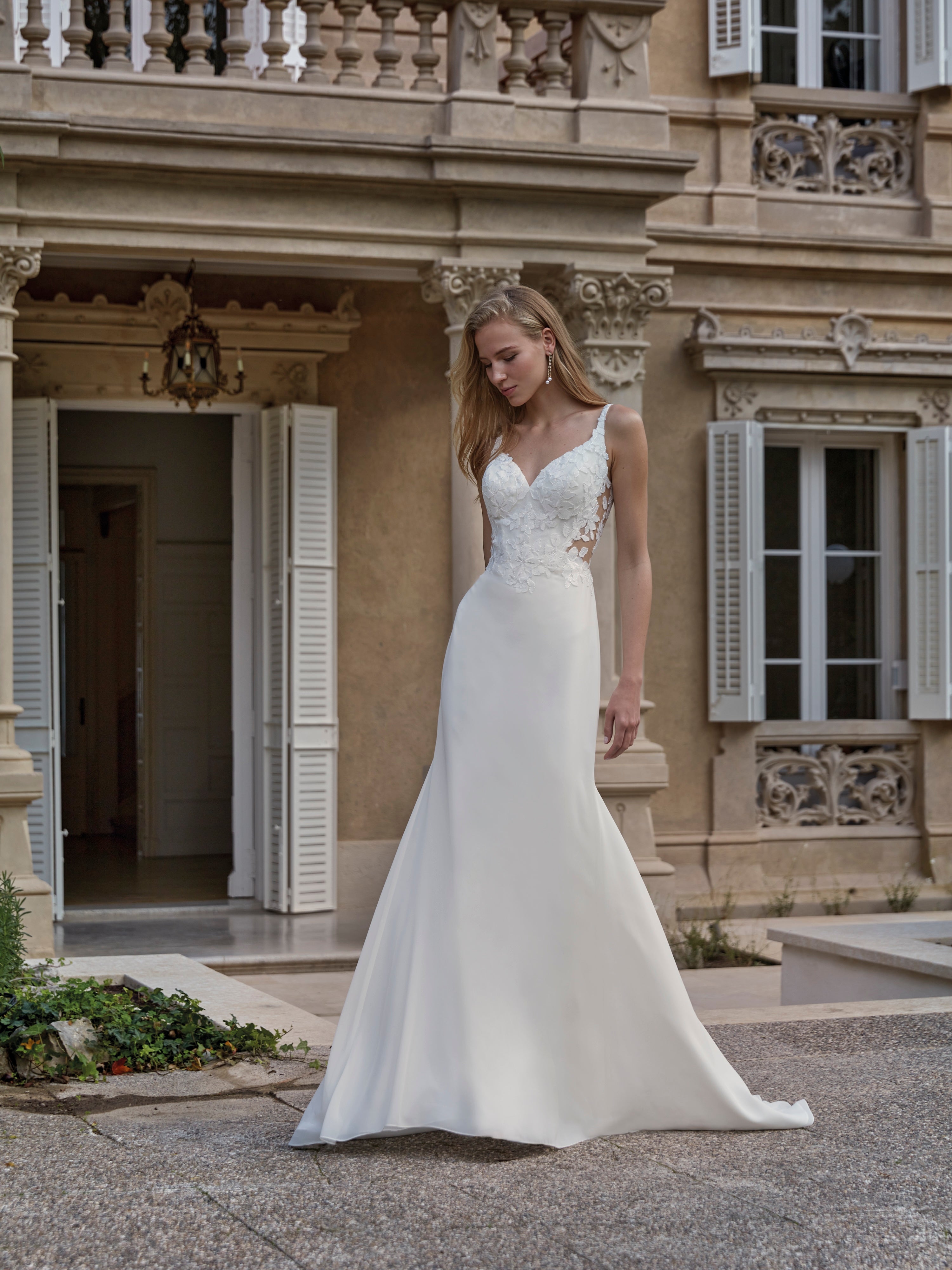 Woman in a white wedding dress standing in front of an elegant building.
