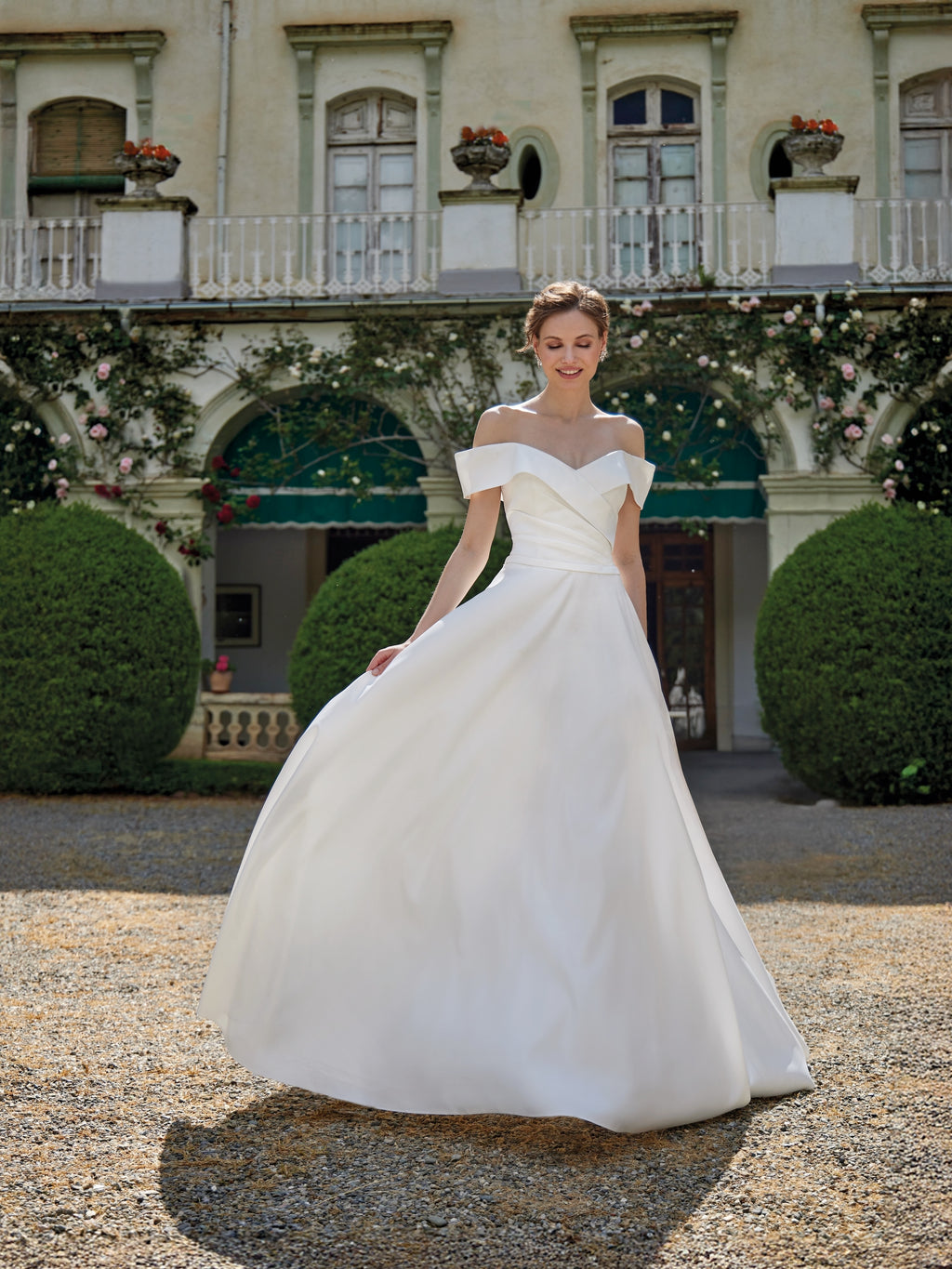 Woman in a white wedding dress standing in front of an elegant building with greenery.