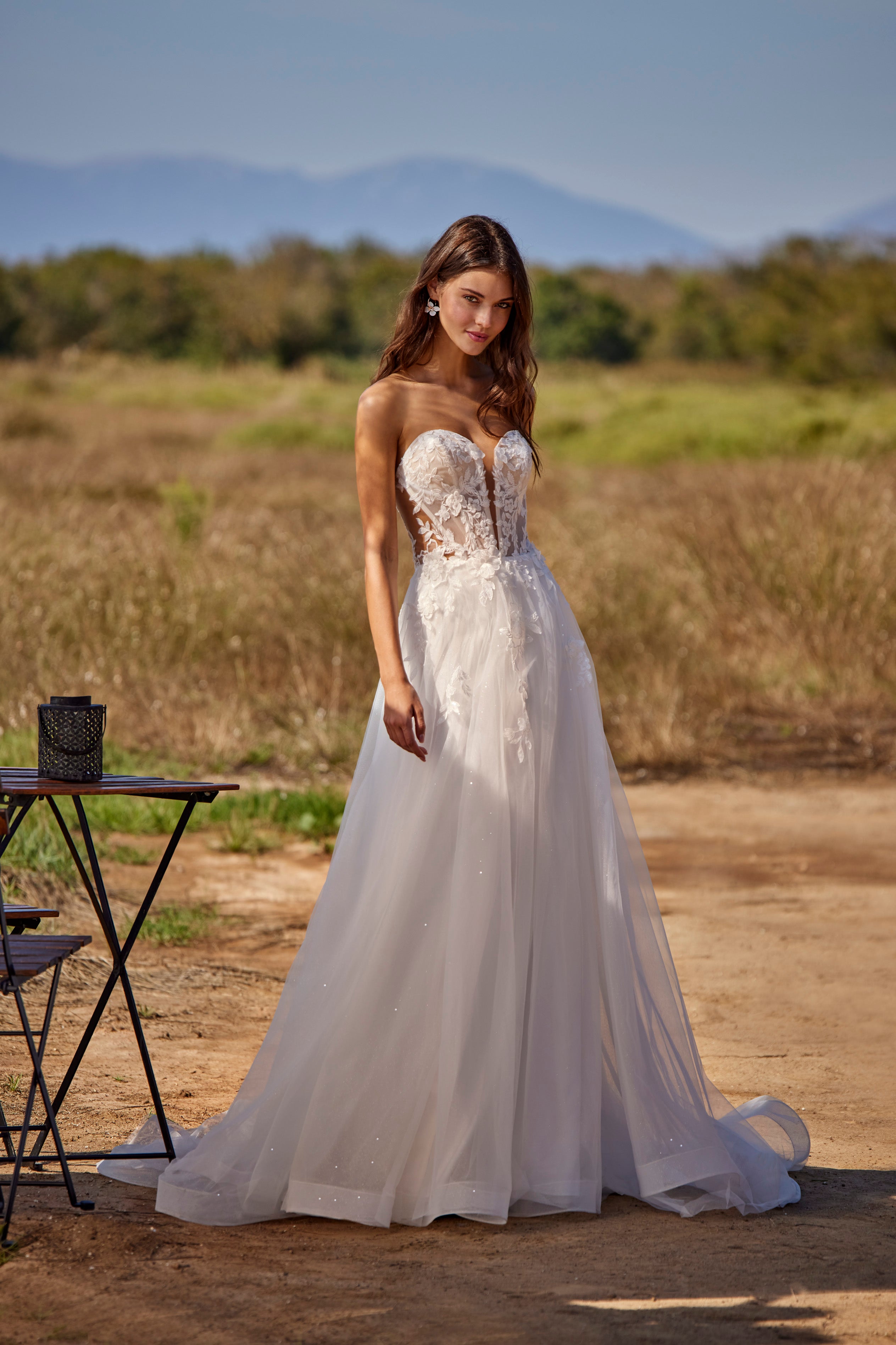 Woman in a white wedding dress standing in a natural setting with mountains in the background