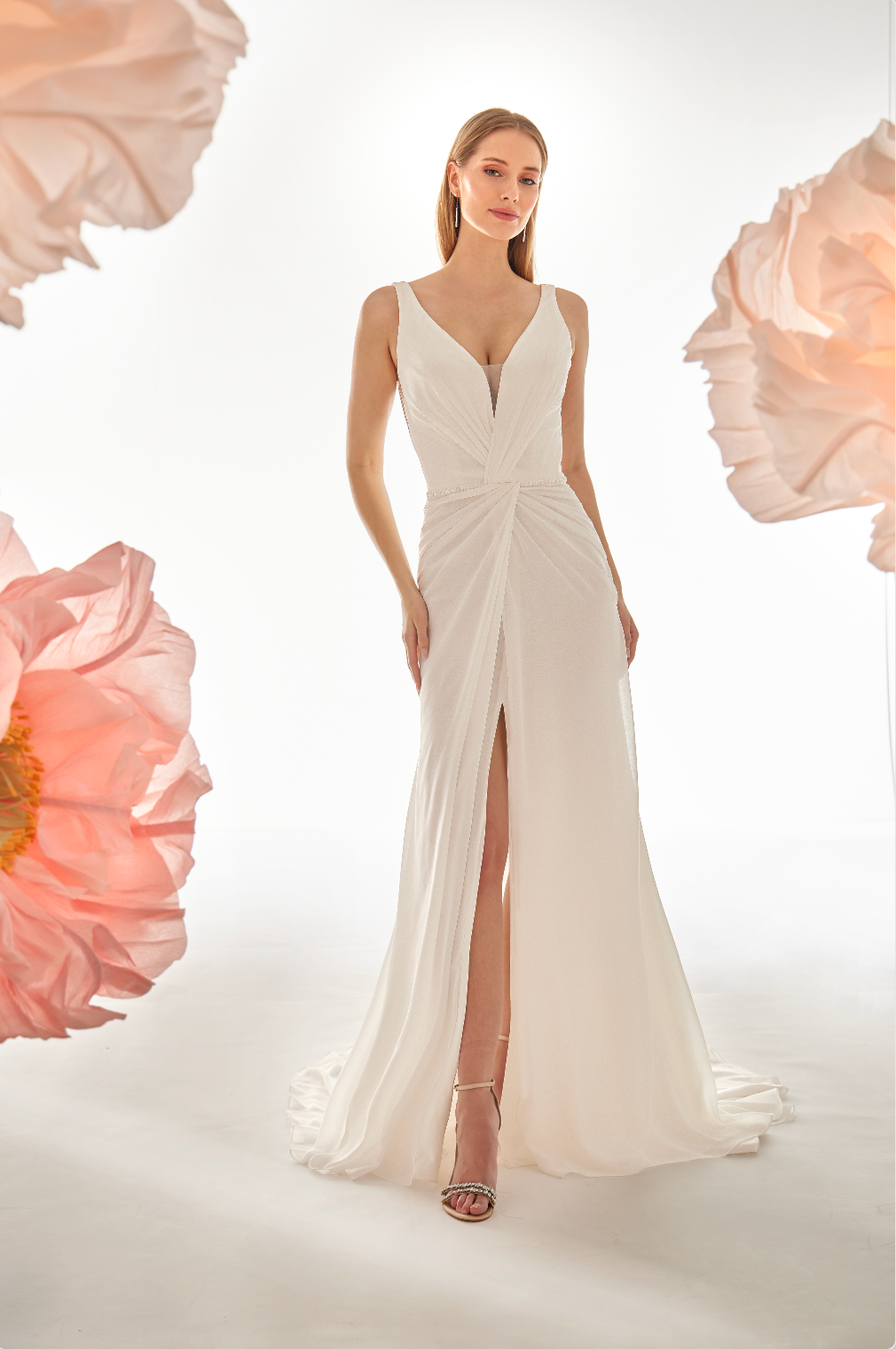 Woman wearing a white evening gown with floral decorations in the background