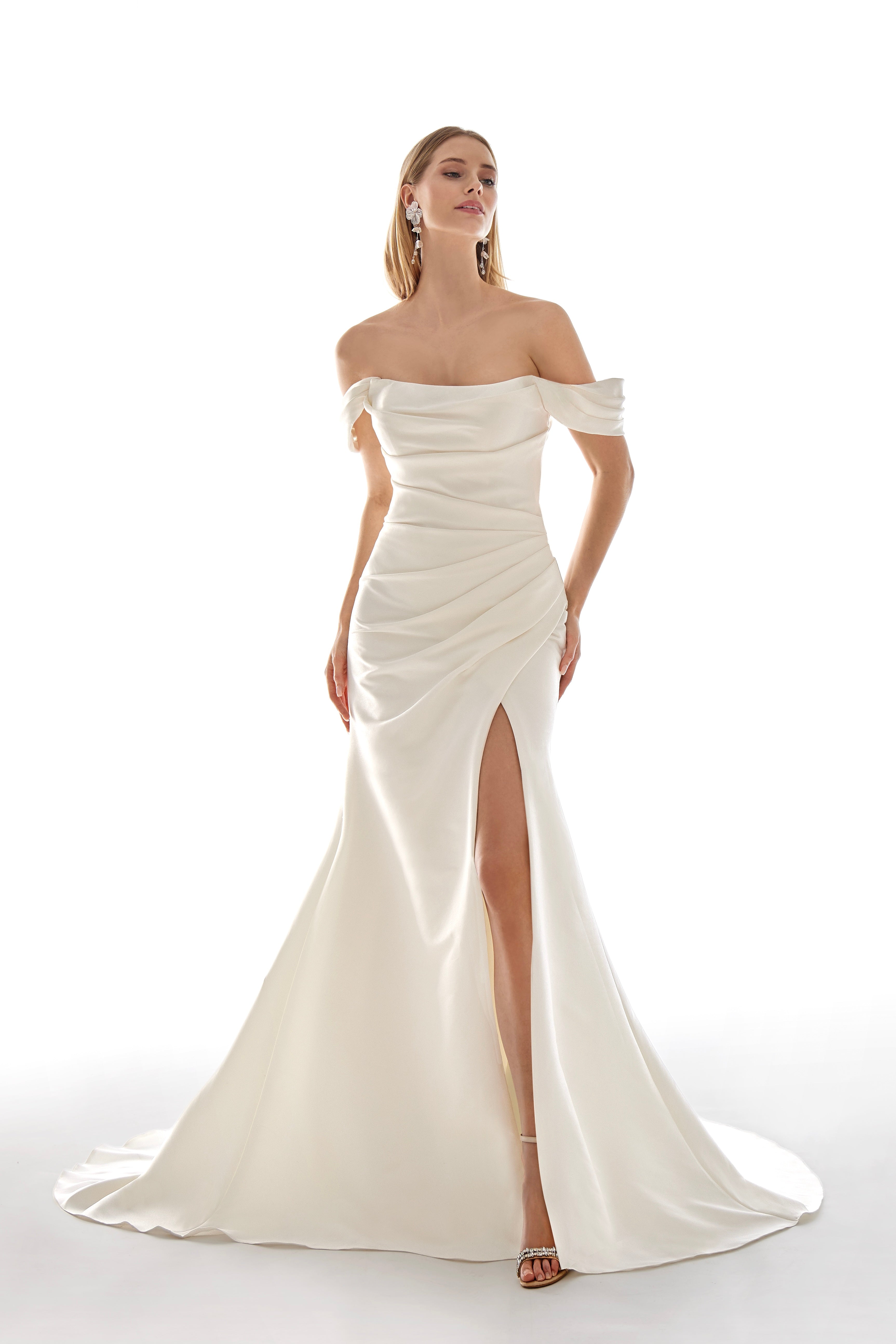 Woman wearing a white off-shoulder gown with a high slit on a white background