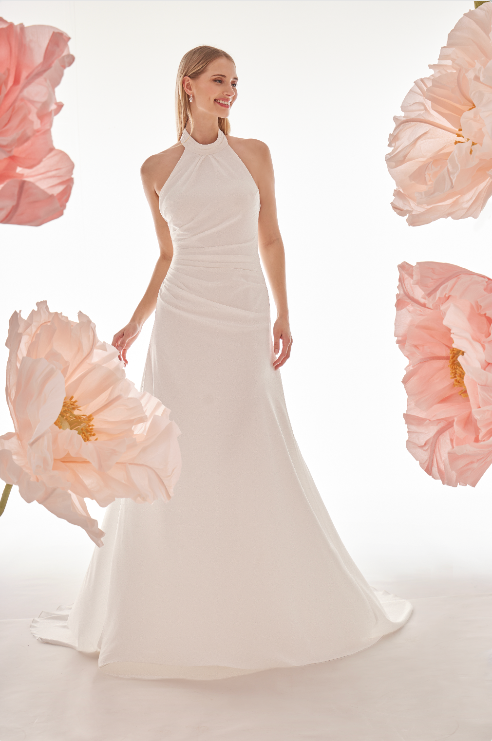 Woman in a white wedding dress surrounded by pink flowers on a light background