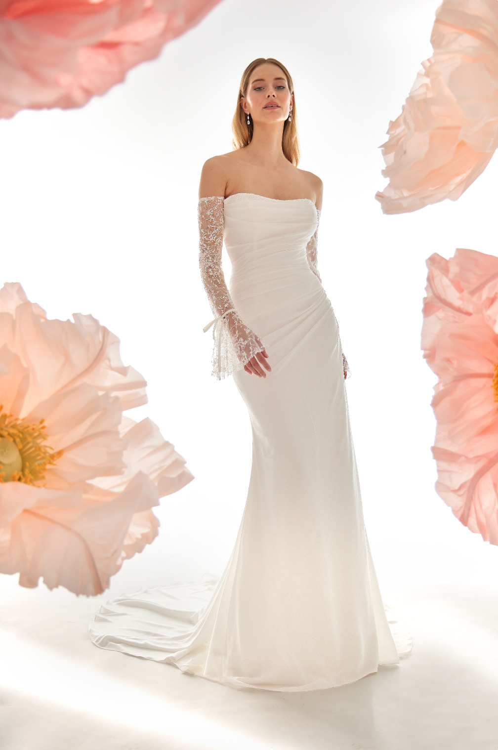 Woman in a white wedding dress with lace sleeves against a floral background